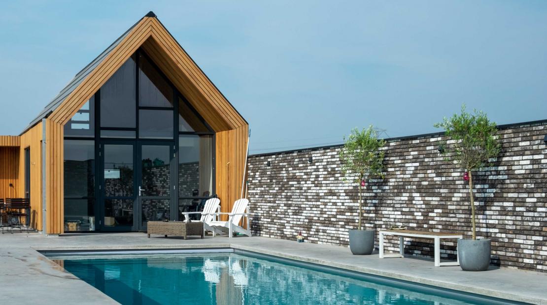 Modern buitenbad met betonnen terras en pool house
